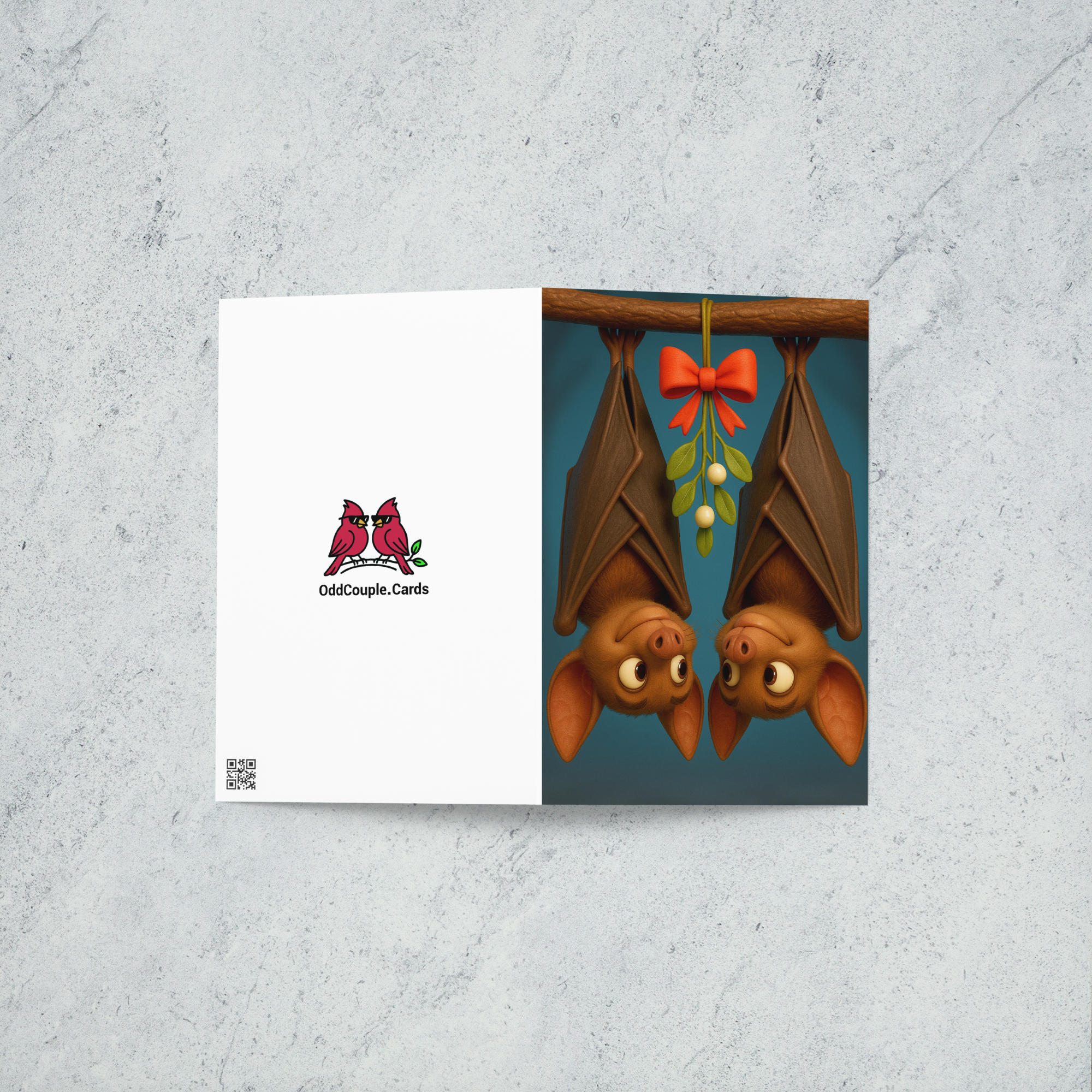 A holiday card featuring two bats smiling at each other as they hang from a branch with mistletoe between the two of them.